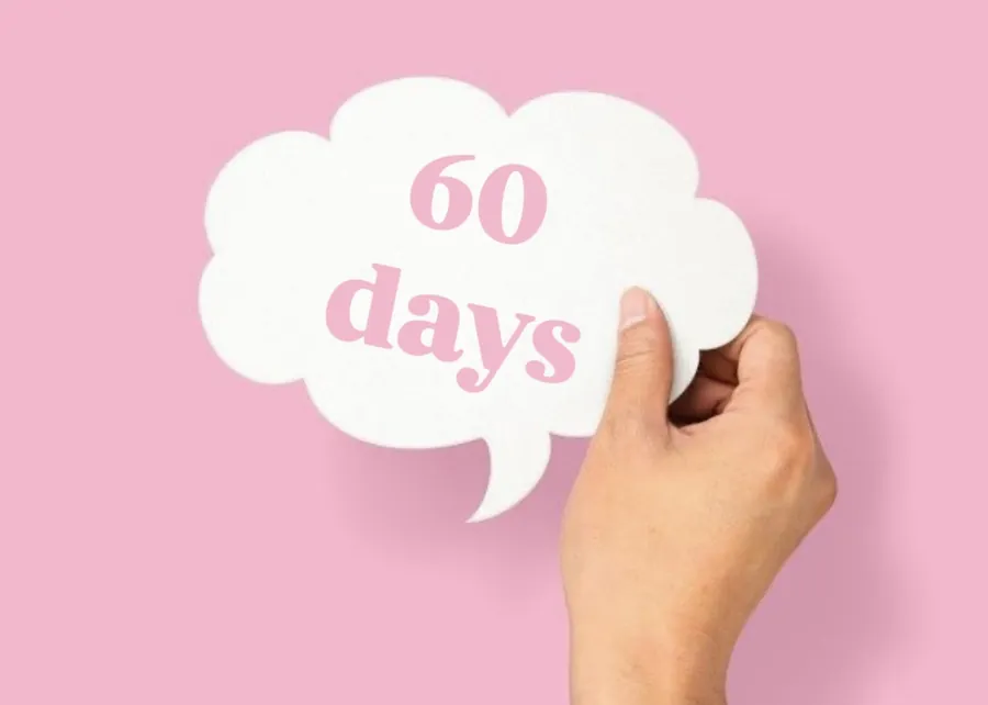 A hand holding a white speech-bubble-shaped sign with the text “60 days” in pink letters against a pink background.