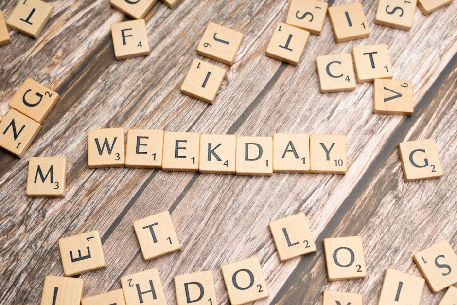 Scattered wooden letter tiles spell 'WEEKDAY' on a rustic wooden surface.