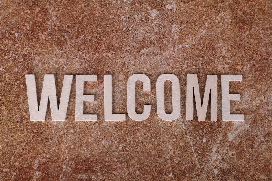 Close-up of a wooden 'Welcome' sign on a textured stone background.