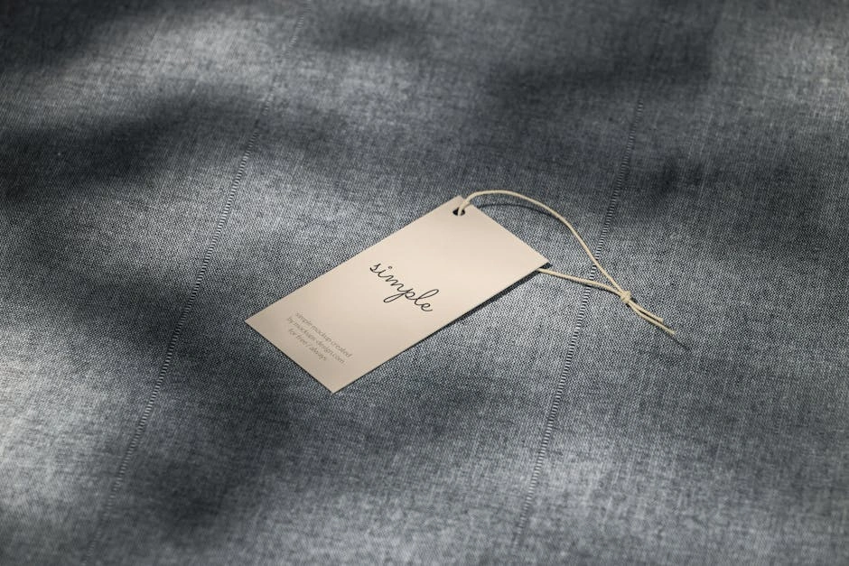 A simple clothing tag resting on a textured gray fabric surface with soft lighting.