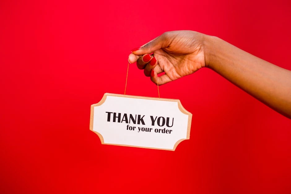 A person holding a thank you sign against a vibrant red background.