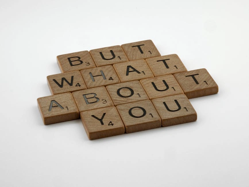 Close-up of wooden Scrabble tiles spelling 'But What About You' on a white surface.