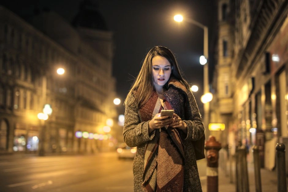 Woman checking her phone at night on a city street